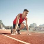 Young male athlete in start position on outdoor track, ready to sprint.