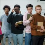 A group of diverse college students posing with books and devices indoors.